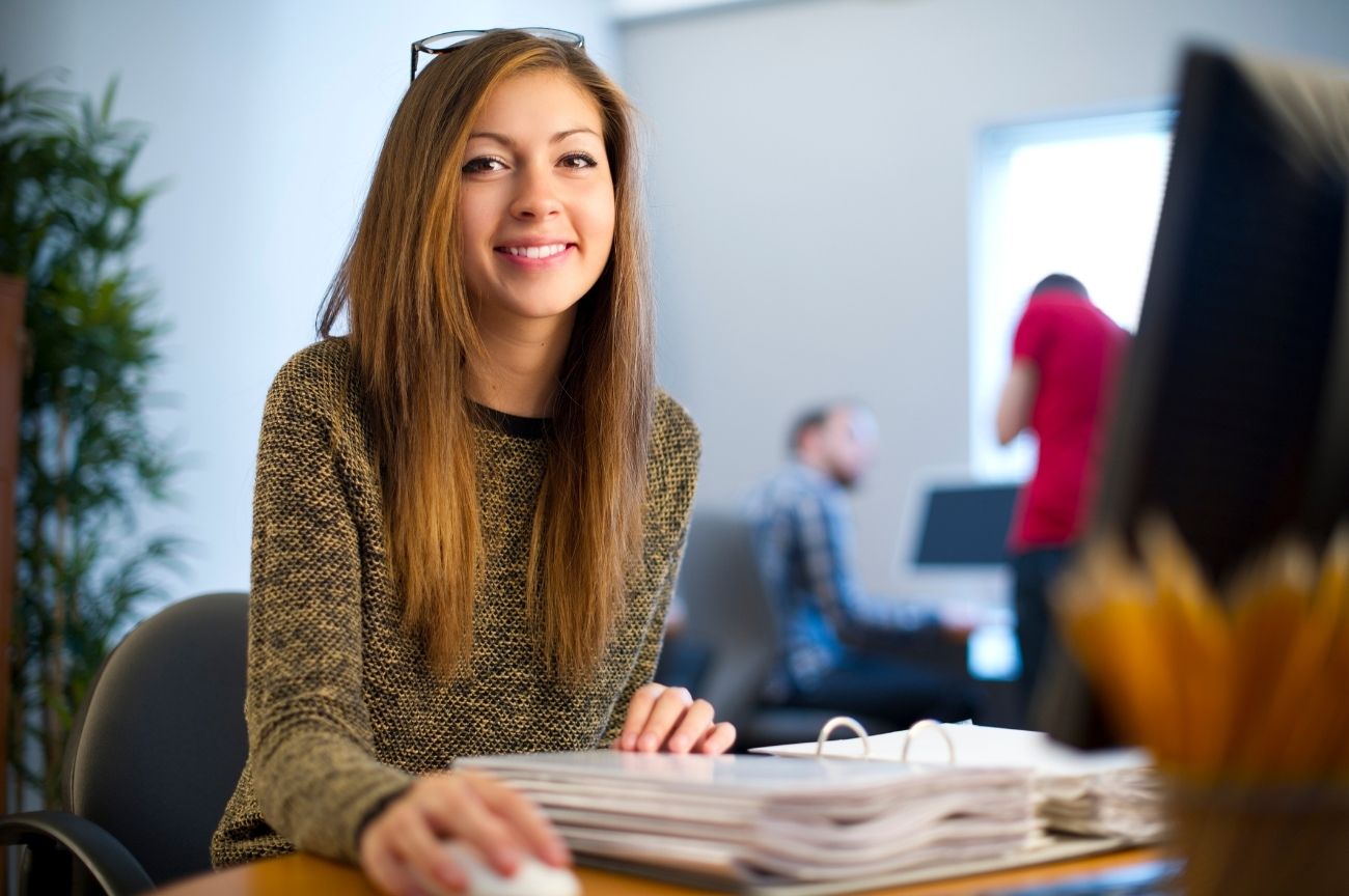 Woman smiles as she sits at her desk.