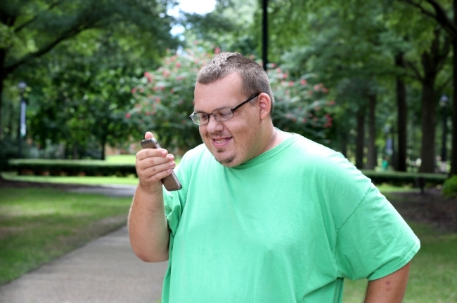 Disabled young man smiles at his phone as he speaks on loudspeaker to a DIAL advisor.