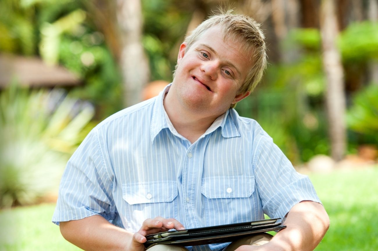 A man with Down syndrome smiles while using a tablet to contact DIAL about rights and discrimination.