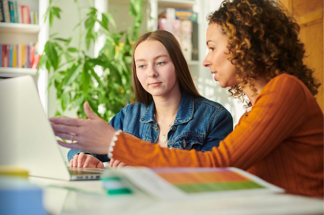 A young woman receives expert guidance as they look at a laptop together.