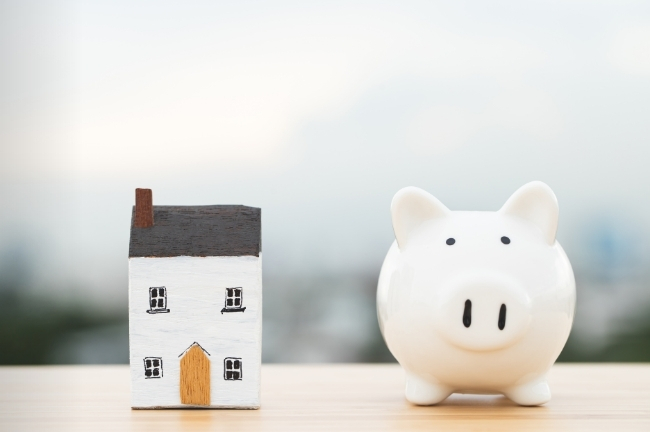 A piggy bank beside a house, symbolising household income.