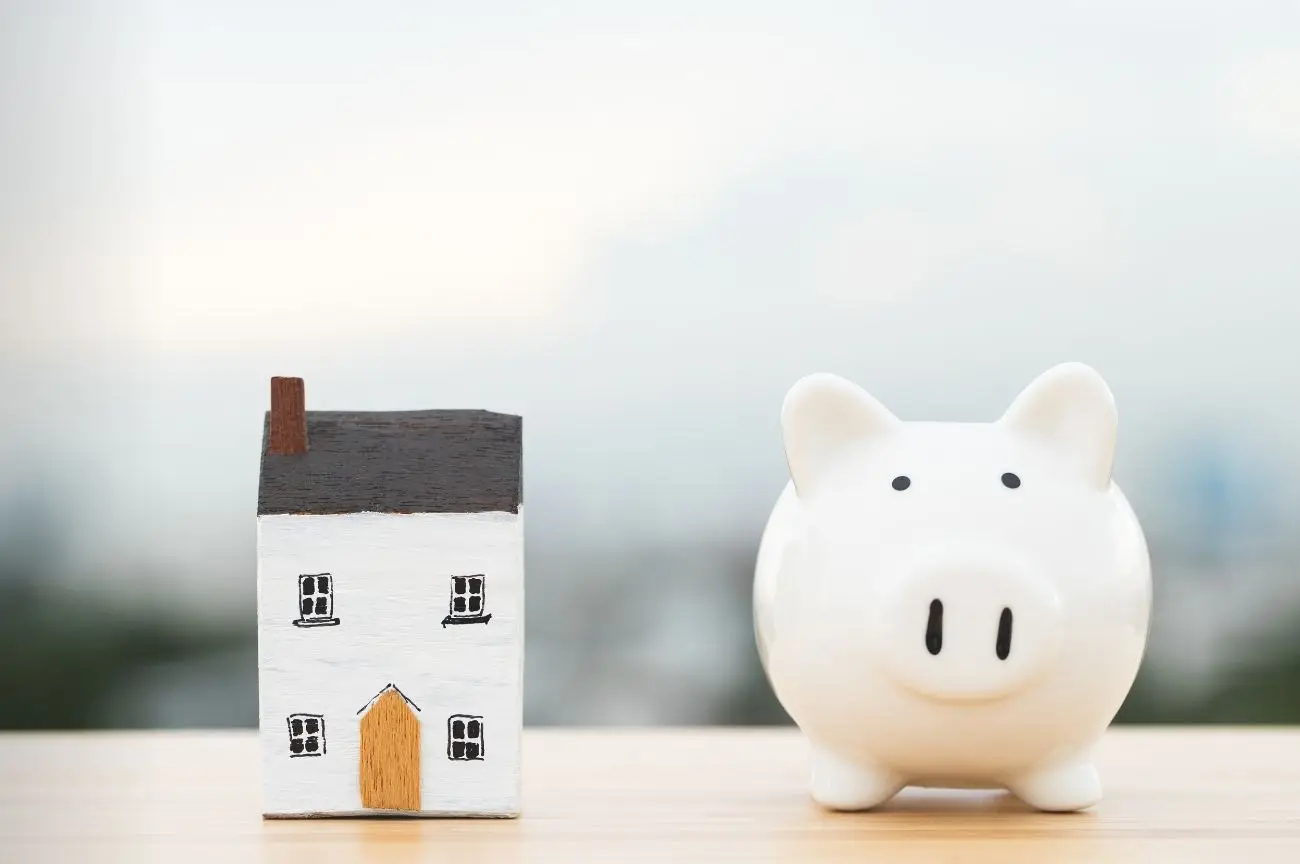 A piggy bank beside a house, symbolising household income.