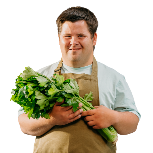 Man in an apron holds some celery as he gets ready to prepare a meal.