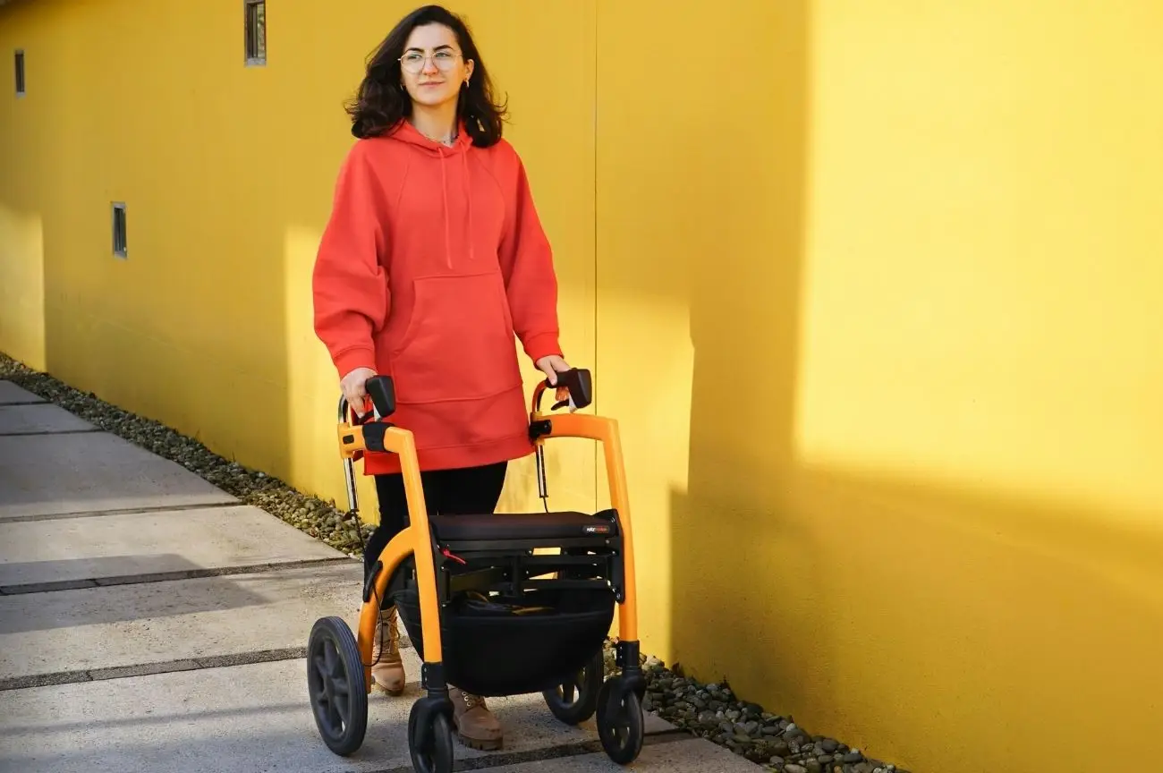 A young woman uses a walking frame to support her mobility.