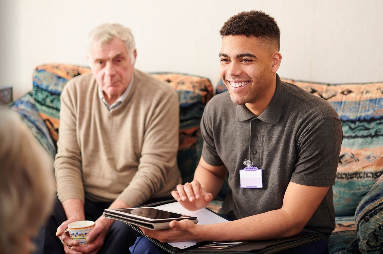 Bank PA smiles as he is talking to the person he is supporting and their family.