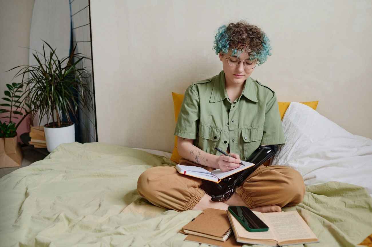 A woman with a prosthetic arm makes notes in her diary to manage her budget.