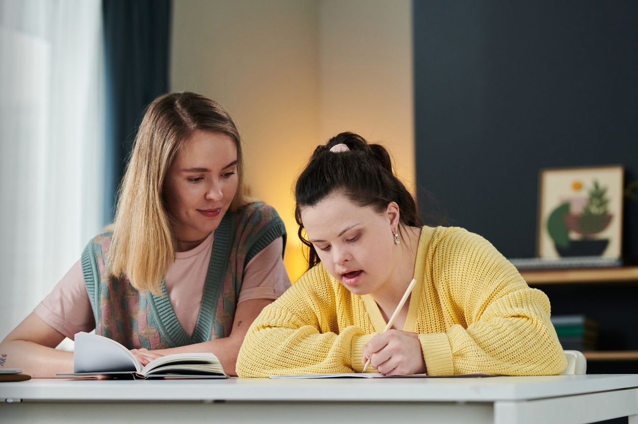 Two people sit together as they talk through a PAMAS registration form.