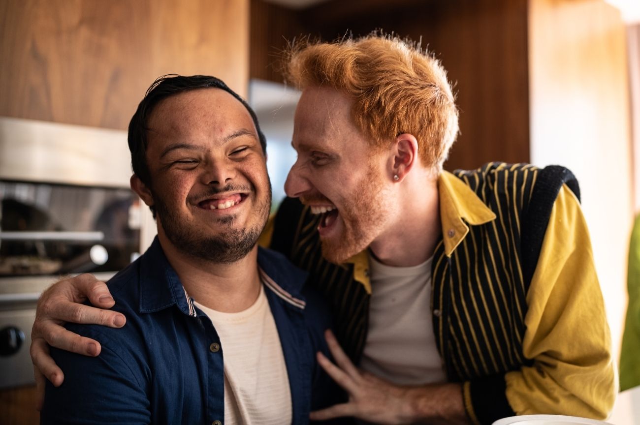 A man shares a laugh with his PA, who has his arm around him.
