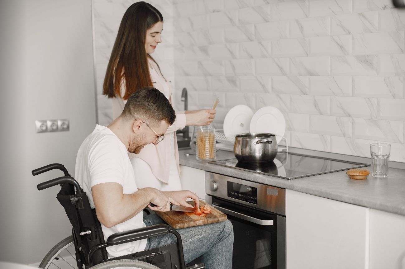 A woman helps a man to cook during his reablement support.