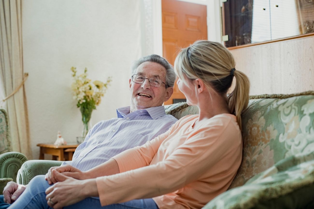 A young woman looks thoughtfully at an older man, suggesting a caring relationship.