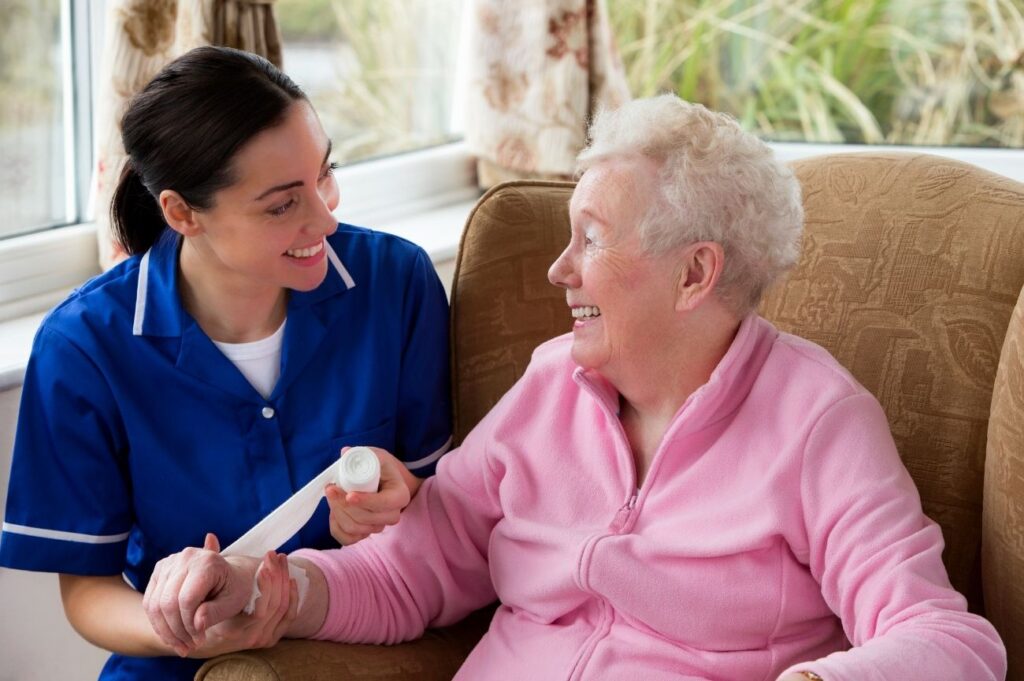 Nurse applying a bandage to a lady in a nursing home.
